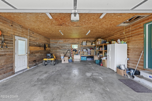 garage featuring wooden walls and white refrigerator with ice dispenser