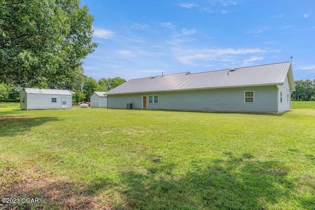 rear view of house featuring a storage unit and a yard