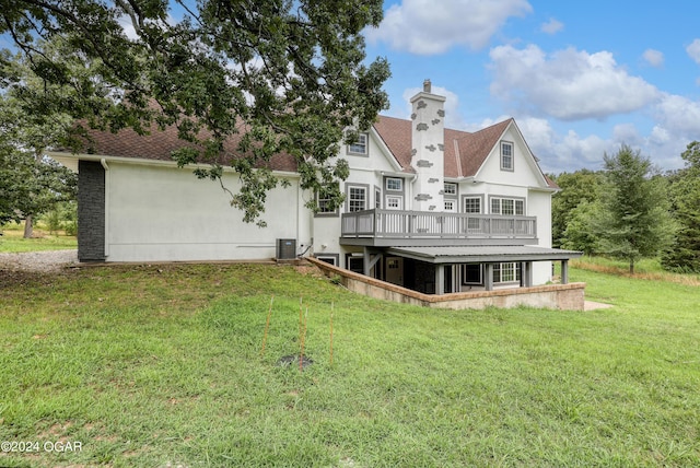 back of property with a deck, central air condition unit, and a lawn