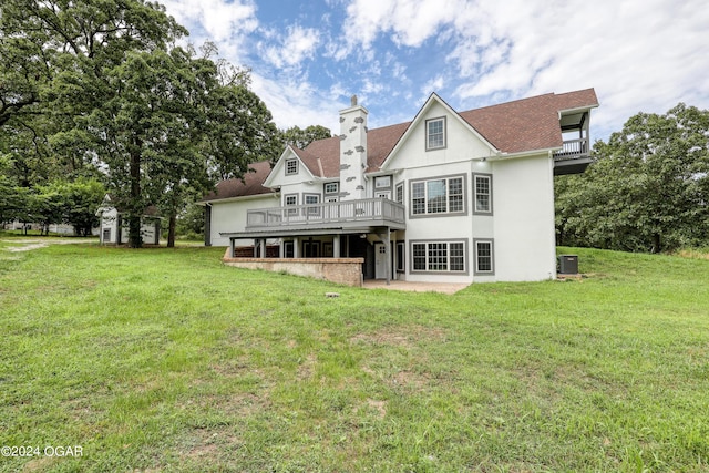 rear view of house with a balcony, a deck, a lawn, and central AC