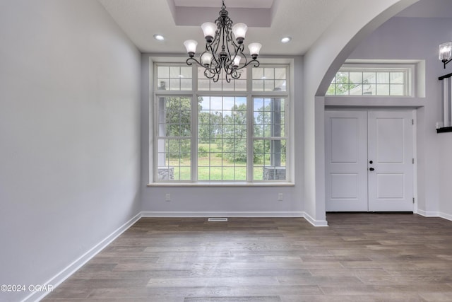 foyer entrance featuring hardwood / wood-style flooring, a wealth of natural light, and an inviting chandelier