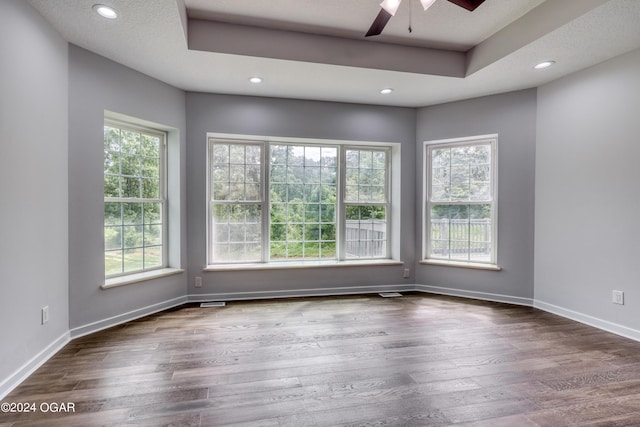 empty room featuring ceiling fan, dark hardwood / wood-style floors, and a tray ceiling