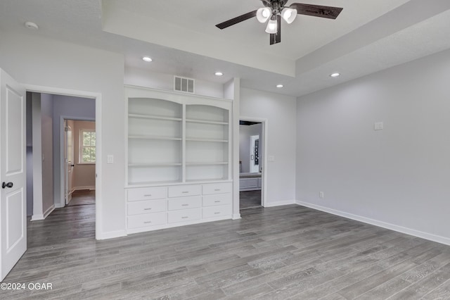 unfurnished bedroom featuring ceiling fan, a tray ceiling, and light hardwood / wood-style floors