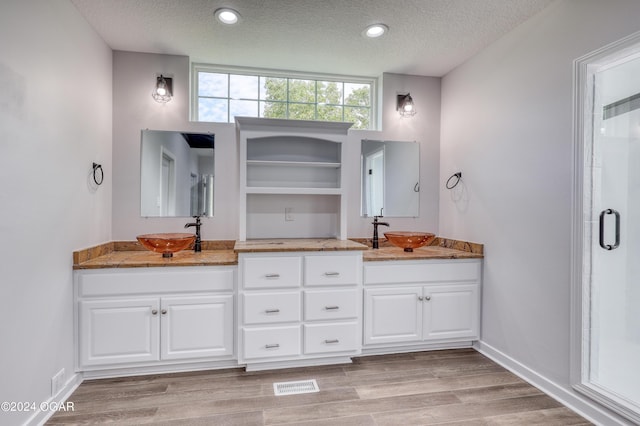 bathroom with walk in shower, vanity, wood-type flooring, and a textured ceiling