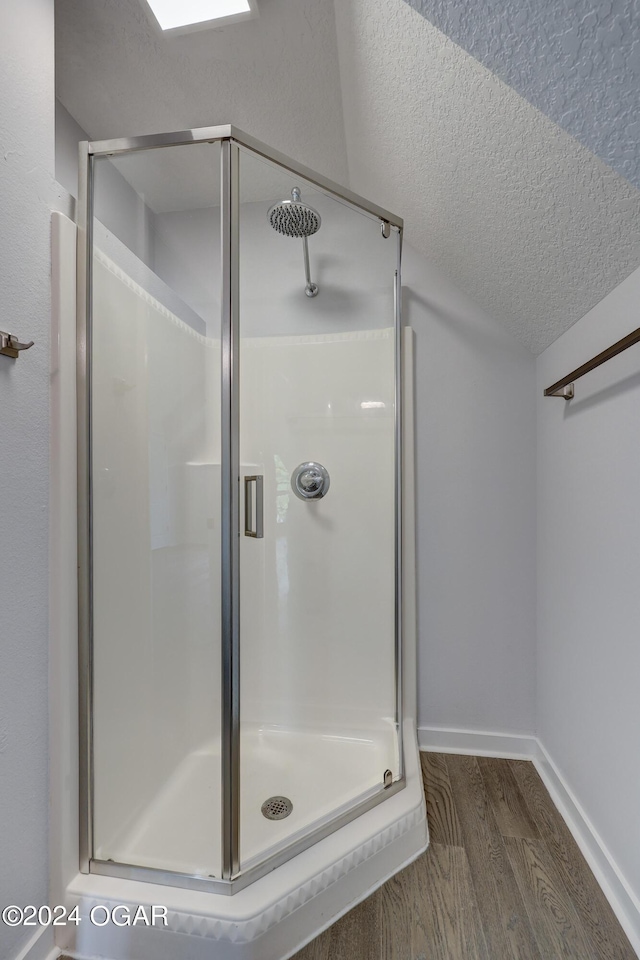 bathroom with wood-type flooring, an enclosed shower, and a textured ceiling