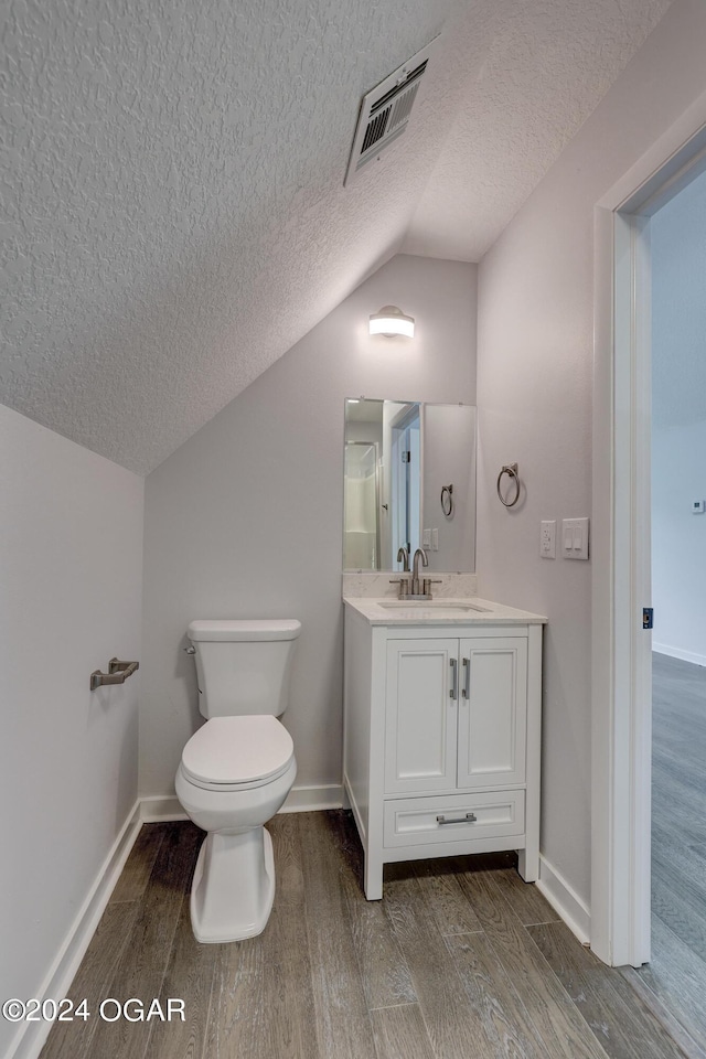 bathroom with vaulted ceiling, toilet, a textured ceiling, and hardwood / wood-style flooring