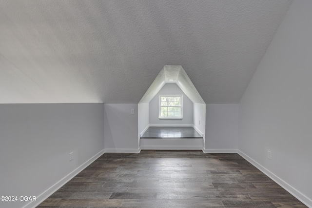 bonus room with dark wood-type flooring, a textured ceiling, and lofted ceiling