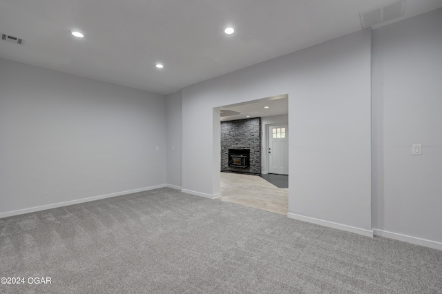 unfurnished living room featuring light carpet and a wood stove