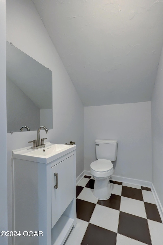 bathroom featuring toilet, vanity, and lofted ceiling