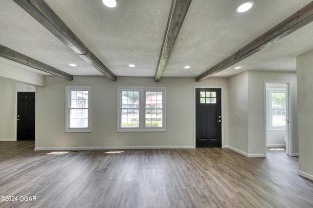 foyer entrance with beamed ceiling, light hardwood / wood-style floors, a textured ceiling, and a wealth of natural light