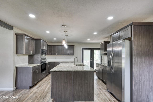 kitchen featuring sink, hanging light fixtures, light hardwood / wood-style flooring, stainless steel refrigerator with ice dispenser, and a center island with sink