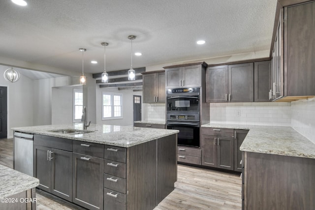 kitchen with stainless steel dishwasher, sink, an island with sink, and tasteful backsplash