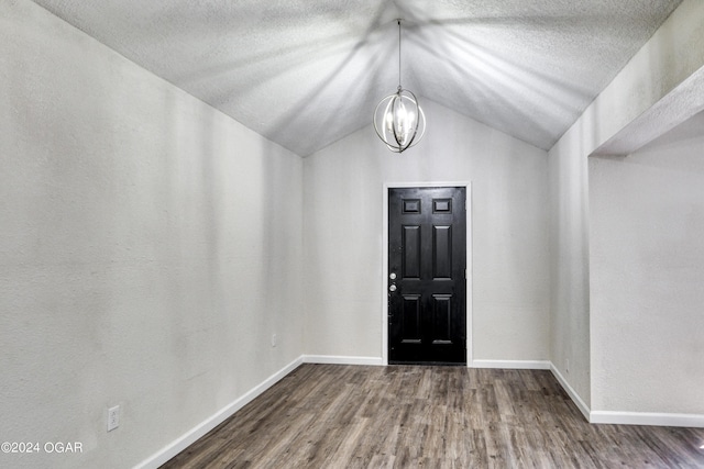 entrance foyer with hardwood / wood-style floors, vaulted ceiling, and a notable chandelier