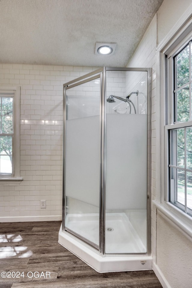 bathroom with wood-type flooring, a textured ceiling, and an enclosed shower