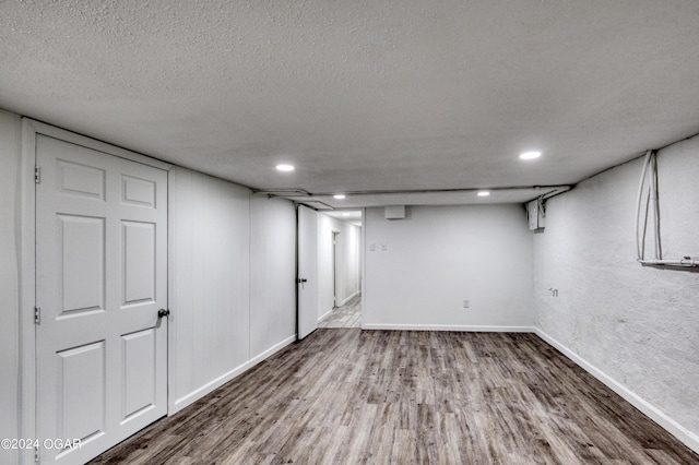 basement featuring hardwood / wood-style flooring and a textured ceiling