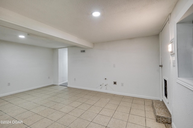 basement featuring light tile patterned flooring and a textured ceiling