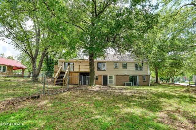 rear view of property featuring central AC, a yard, and a deck