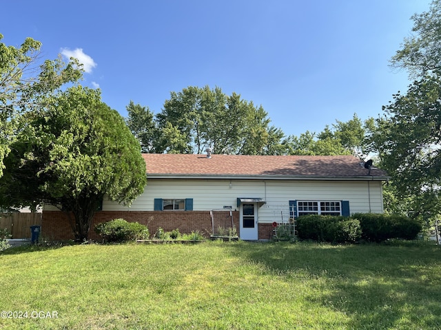 back of house with a yard, fence, and brick siding