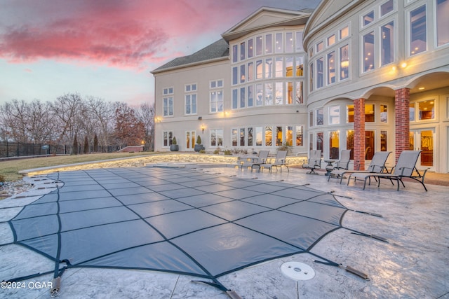 pool at dusk featuring a patio