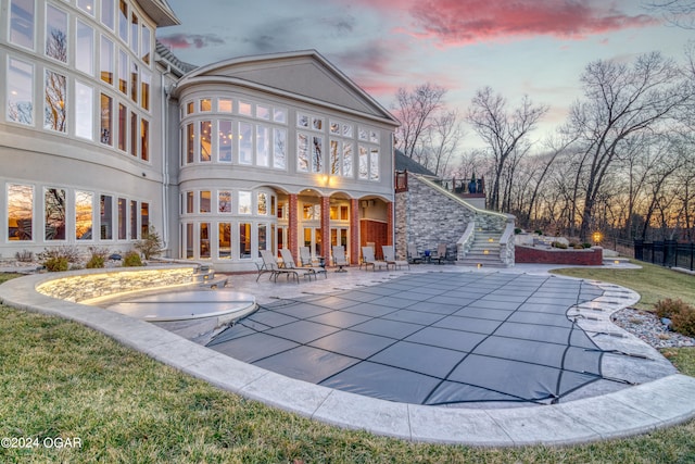 back house at dusk with a patio and a covered pool