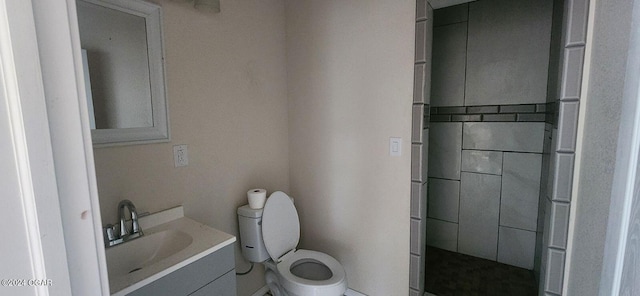 bathroom featuring a shower with shower door, vanity, and toilet