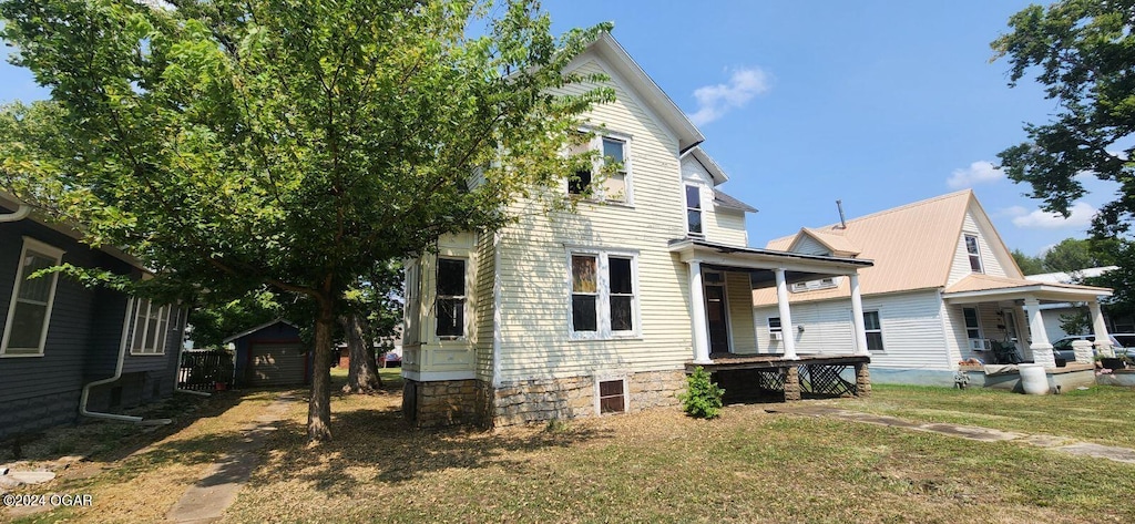 view of side of home with covered porch, an outdoor structure, and a yard