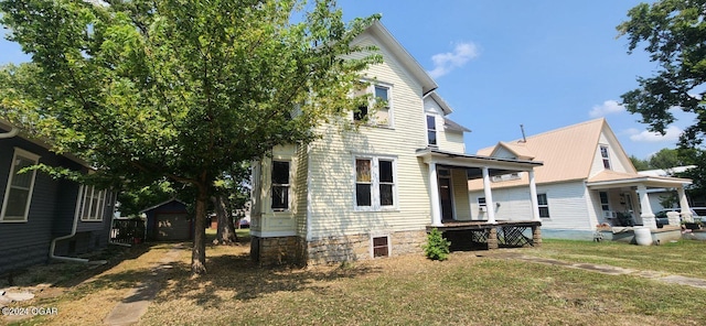 view of side of home with covered porch, an outdoor structure, and a yard