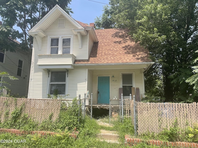 view of front of property with a porch, a fenced front yard, and a shingled roof