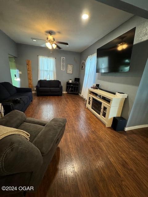 living room featuring dark wood-type flooring and ceiling fan