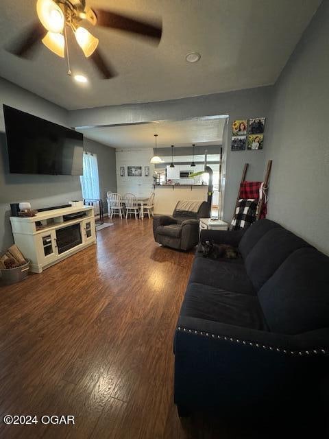 living room featuring ceiling fan, dark hardwood / wood-style floors, and plenty of natural light