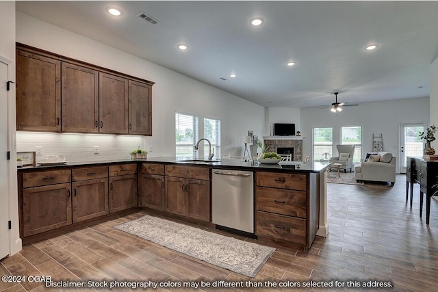 kitchen with stainless steel dishwasher, kitchen peninsula, hardwood / wood-style flooring, and backsplash