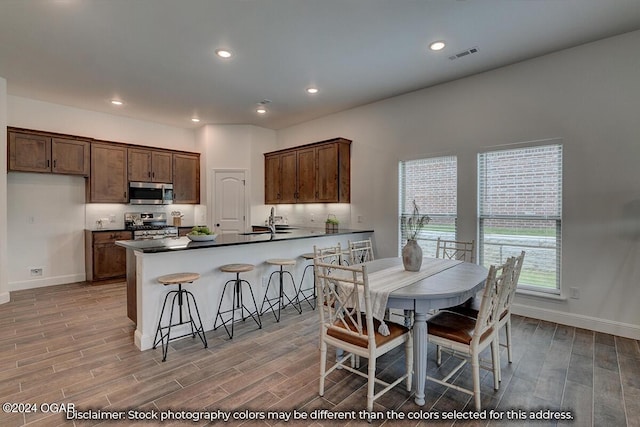 kitchen with stove, sink, kitchen peninsula, decorative backsplash, and light wood-type flooring