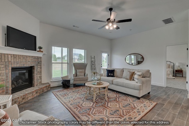 living room featuring wood-type flooring, a brick fireplace, and ceiling fan