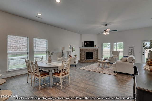 dining space with a brick fireplace, hardwood / wood-style floors, and ceiling fan