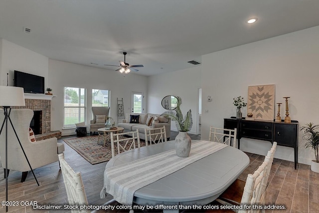 dining area featuring ceiling fan and a brick fireplace