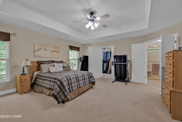 bedroom featuring ceiling fan, a spacious closet, light carpet, a tray ceiling, and connected bathroom