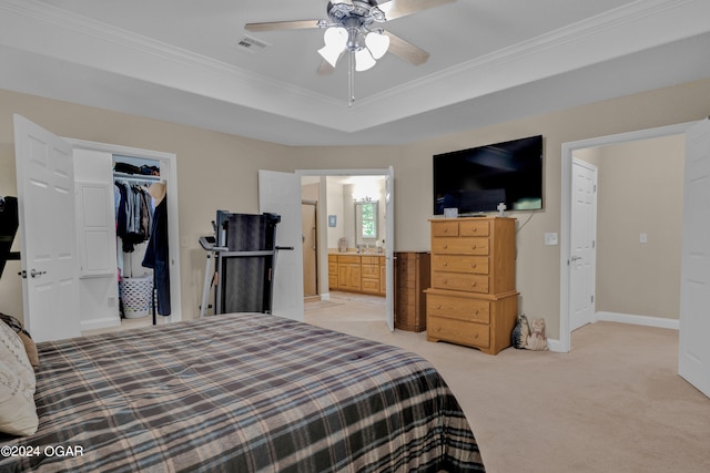 bedroom with a tray ceiling, a closet, ceiling fan, light carpet, and ensuite bathroom