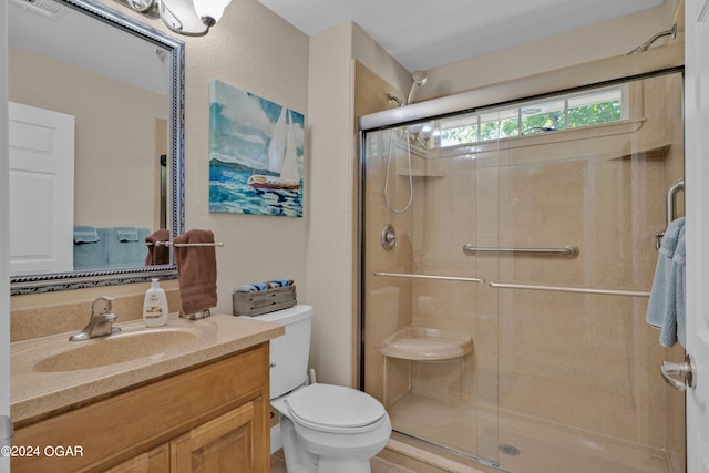 bathroom featuring a shower with door, vanity, and toilet