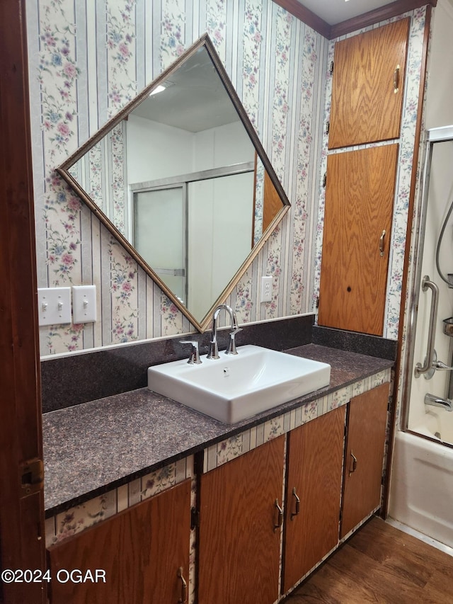 bathroom featuring hardwood / wood-style flooring, bath / shower combo with glass door, and vanity