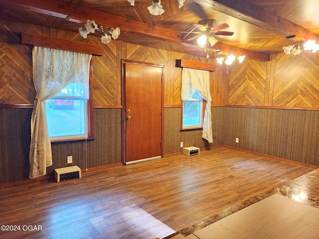 additional living space featuring a wealth of natural light, wood-type flooring, beamed ceiling, and wood walls