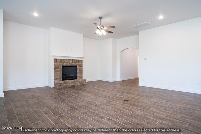 unfurnished living room with ceiling fan, dark hardwood / wood-style flooring, and a brick fireplace