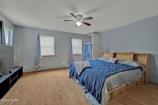 bedroom with ceiling fan, a textured ceiling, and light hardwood / wood-style floors