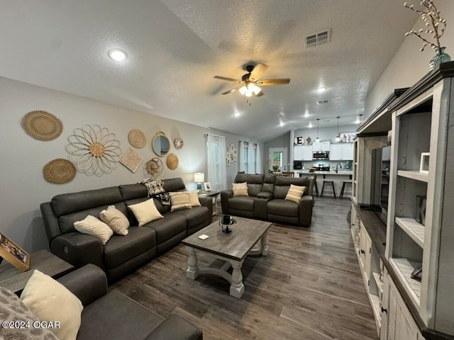 living room with dark hardwood / wood-style flooring, a textured ceiling, vaulted ceiling, ceiling fan, and sink