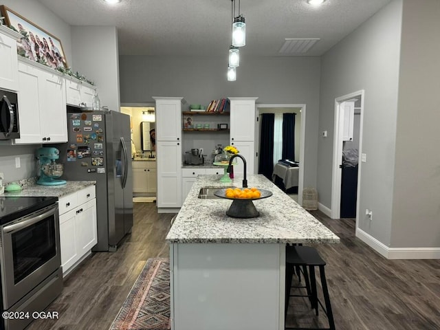 kitchen with appliances with stainless steel finishes, white cabinets, and an island with sink