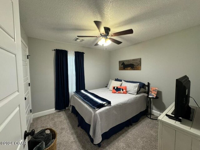 carpeted bedroom featuring ceiling fan and a textured ceiling