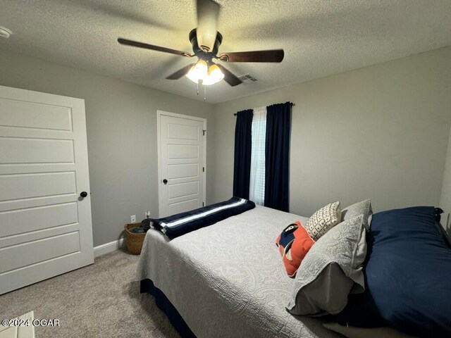 bedroom with ceiling fan, a textured ceiling, and carpet