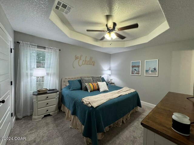 carpeted bedroom featuring ceiling fan, a textured ceiling, and a tray ceiling