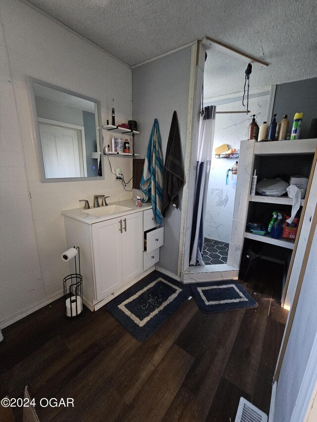 bathroom with a textured ceiling, curtained shower, vanity, and hardwood / wood-style floors