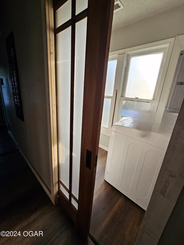 hall with washer / clothes dryer, dark hardwood / wood-style flooring, and a textured ceiling