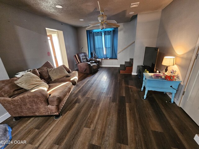 living room featuring a textured ceiling, ceiling fan, and dark hardwood / wood-style floors